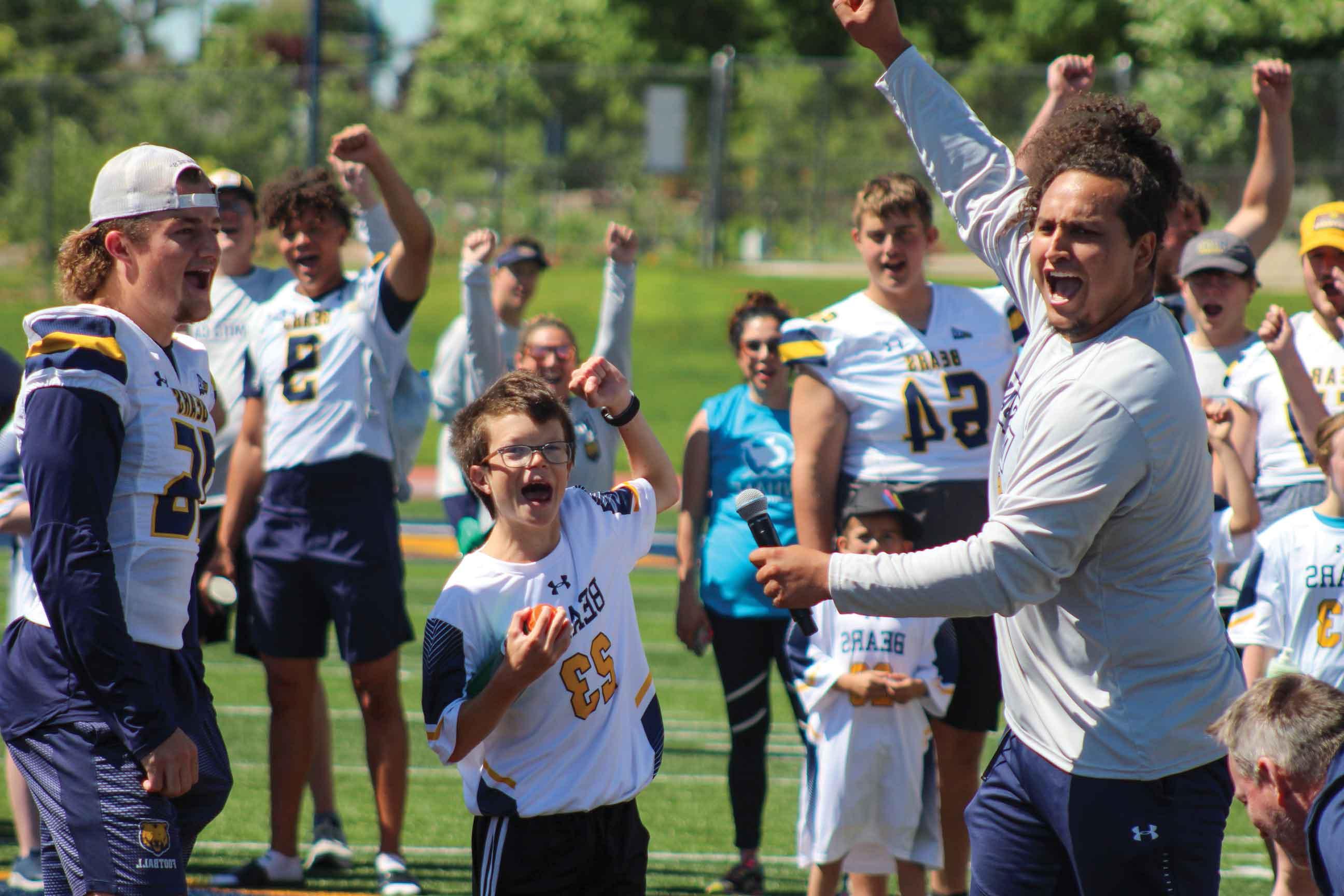 UNC football student-athletes on the field, accompanied by disabled children during the No Limits Camp, fostering inclusivity and joy.